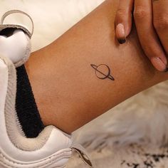 a woman's arm with a small saturn tattoo on the left side of her leg