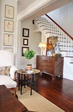 a living room filled with furniture next to a stair case and wooden floored stairs