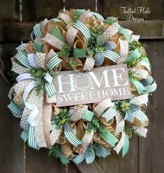 a wreath that says home sweet home hanging on the front door with ribbon and bows