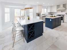 a large kitchen with an island and wine rack in the center, surrounded by white cabinets