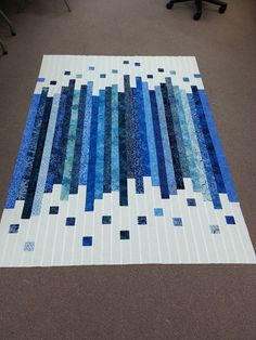 a blue and white quilt sitting on top of a floor next to a computer desk