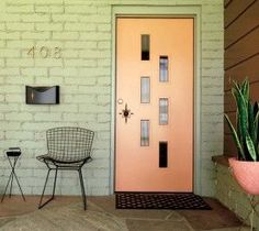 a pink door with two chairs and a potted plant on the front porch next to it