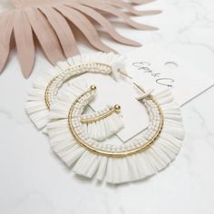 These White Beaded Raffia Hoops are perfect for adding a touch of elegance to any outfit. Their lightweight design ensures comfortable wear for all-day use. Crafted with precision, these earrings are a must-have for any fashion-forward individual. 2” Lead and nickel free. Elegant Woven Earrings For Spring, Elegant Summer Beach Hoop Earrings, White Elegant Woven Jewelry, Elegant White Woven Jewelry, Chic Adjustable Hoop Earrings For Summer, Fringe Earrings For Vacation, Elegant Handmade Hoop Earrings For Vacation, Trendy White Tassel Earrings For Summer, Chic Summer Jewelry With Tassels