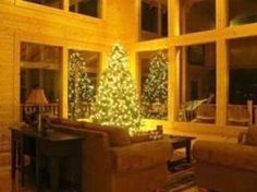 a living room filled with furniture and a lit up christmas tree in the middle of it