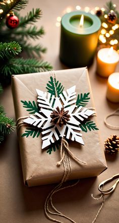 a present wrapped in brown paper with a snowflake decoration on it next to candles