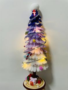 a christmas tree made out of feathers on top of a wooden stand with a white background