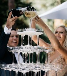 a man and woman are pouring champagne into wine goblets at a wedding reception