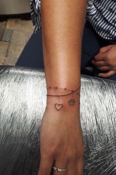 a woman's wrist with a dog paw and heart tattoo on the left hand