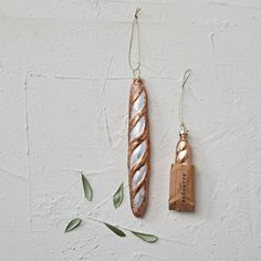 two pieces of bread hanging from hooks on a white wall with green leaves around them