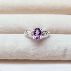 an amethorate and diamond ring sitting on top of a white cloth