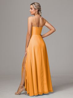 a woman in an orange dress is standing with her back turned to the camera and looking down