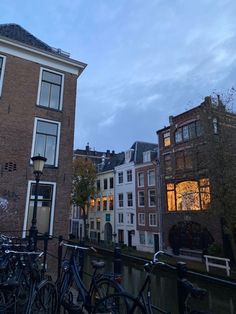 several bicycles parked next to each other on the side of a river in front of buildings