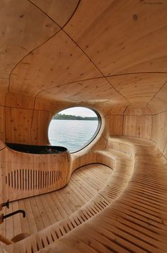 the inside of a wooden boat with a circular window on it's side and water in the background