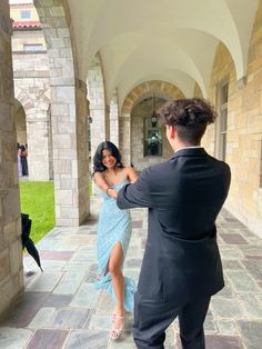 a man in a suit and woman in a blue dress are dancing on the stone walkway