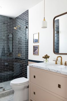 a white toilet sitting under a bathroom mirror next to a walk in shower and sink