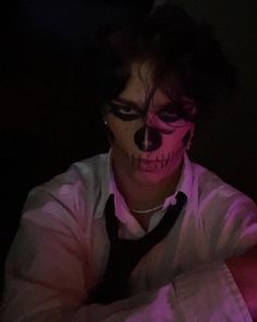 a man with his face painted like a skeleton wearing a tie and makeup is looking at the camera