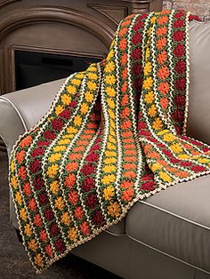 a crocheted blanket sitting on top of a couch next to a fire place