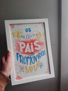 a person holding up a framed poster with the words in spanish and english on it