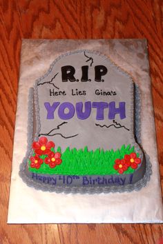 a birthday cake for a young boy with flowers on the front and side, sitting on top of a wooden table