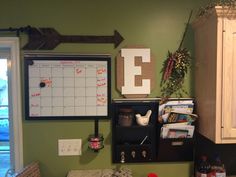 a kitchen with green walls and a whiteboard on the wall next to a counter