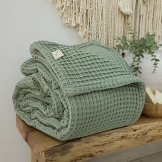 a green blanket sitting on top of a wooden table next to an apple and plant