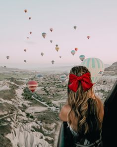 a woman looking at hot air balloons in the sky