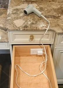 an electrical cord is plugged into a drawer in a kitchen with marble countertops