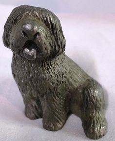 a small dog figurine sitting on top of a white surface with it's mouth open