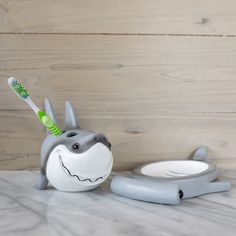 a toothbrush holder that has a shark on it and a tooth brush in the mouth