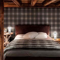 a bed sitting under a wooden ceiling next to a night stand with two lamps on it