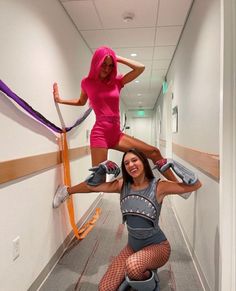 two women in tights and heels are hanging upside down on the floor while one woman is holding onto an orange pole