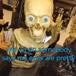 a creepy skeleton with blue eyes sitting on top of a table