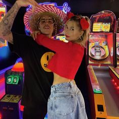 a man and woman standing next to each other in front of a pinball machine