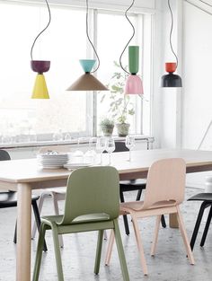 a dining room table with chairs and lights hanging from the ceiling in front of it