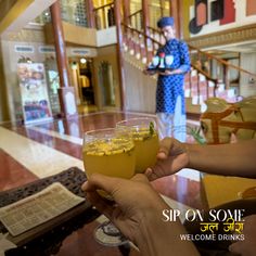 two people holding up wine glasses with drinks in front of them on a hotel lobby