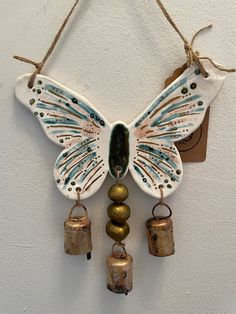 a wall hanging with bells and a butterfly on it's wings, attached to the wall