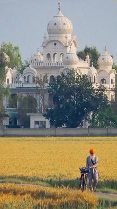 a man with an orange turban walks in front of a large white building