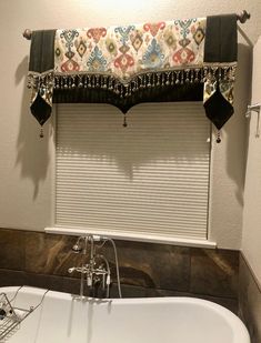 a bath tub sitting next to a window with roller shades on the top and bottom