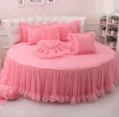 a pink bed with ruffled bedspread and pillows