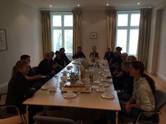 a group of people sitting at a long table with food and drinks in front of them