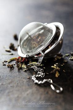 a tea strainer filled with loose leaves on top of a table