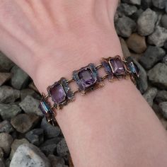 This fantastic vintage bracelet features nine (9) rectangular filigree links each accented with one (1) cut-cornered rectangular modified brilliant cut amethyst set into bezel settings. The links feature a pierced design with engraved details and bordered with milgrain edging. The bracelet measures 6-1/4 inches in length and 15.7mm in width. The bracelet is finished with a spring ring style clasp. The patina on this bracelet is spectacular. Purple Rectangular Jewelry For Formal Occasions, Formal Rectangular Purple Jewelry, Rectangular Bezel Set Formal Jewelry, Unique Rectangular Jewelry For Formal Occasions, Vintage Jewelry With Rectangular Gemstone, Formal Purple Rectangular Jewelry, Formal Rectangular Bezel Set Jewelry, Vintage Rectangular Gemstone Jewelry, Antique Purple Bracelets For Formal Occasions