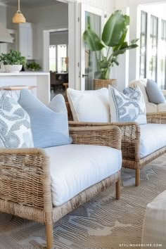 wicker couches with blue and white pillows on them in a living room area