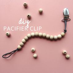 a string of beads and a pair of scissors on a pink background with the words diy pacifier clip