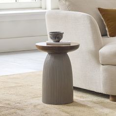 a vase sitting on top of a table next to a white couch in a living room