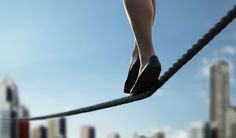 a woman walking across a rope in front of a city