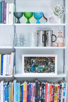 a book shelf filled with lots of books next to glass vases and other items