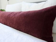 a close up of a pillow on a bed with white sheets and pillows in the background