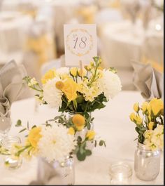 two vases filled with yellow and white flowers sitting on top of a round table