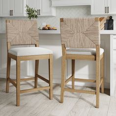 two wooden stools sitting next to each other in front of a white kitchen counter